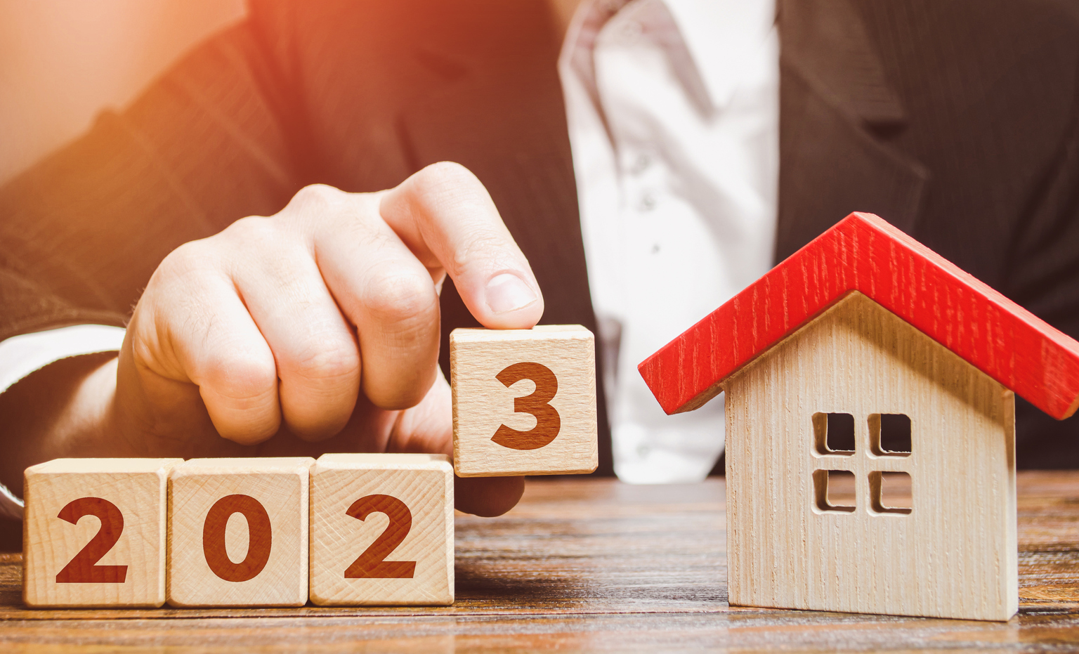 Businessman and 2023 blocks near house.  Real estate price forecasts for the new year.  Trends and changes, new challenges for the economy and impact on the housing market.  Mortgage rate.